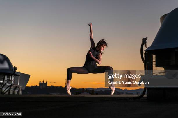 female ballet dancer dancing on a rooftop at sunset in lyon with pointes shoes and bodysuit - oficios de eventos fotografías e imágenes de stock