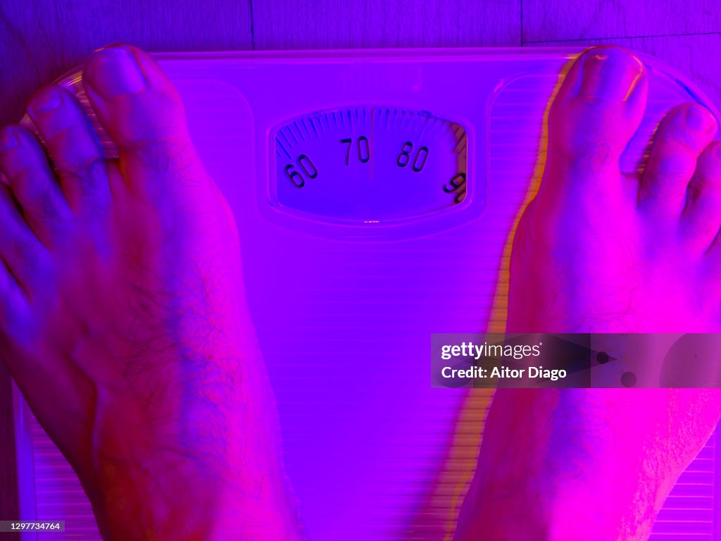 Man measuring his weight on a scale.