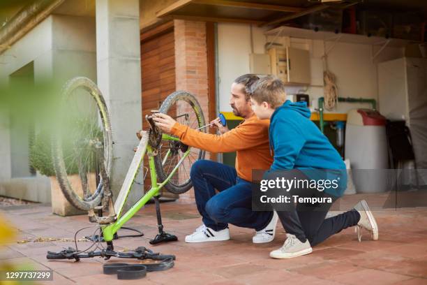 padre e hijo reparando una bicicleta juntos. - family caucasian fotografías e imágenes de stock