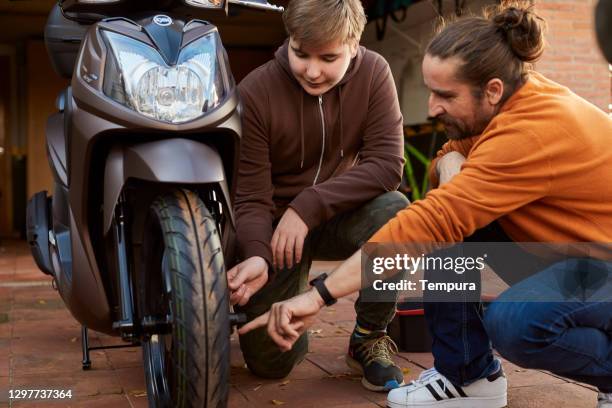 father teaching his son how to repair a scooter. - moped stock pictures, royalty-free photos & images