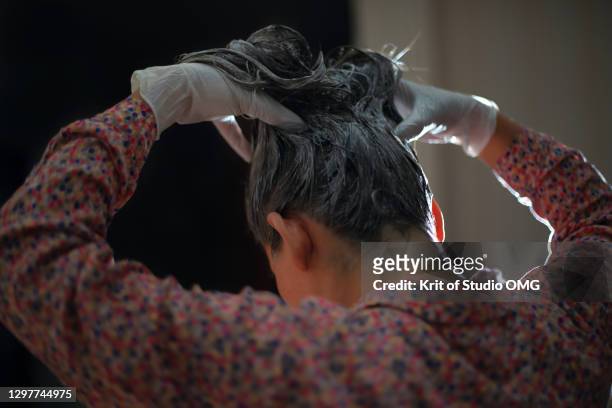 a woman dye her hair by herself - tintura foto e immagini stock