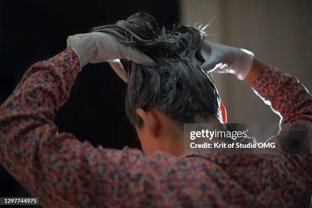 a woman dye her hair by herself - haarkleuring stockfoto's en -beelden