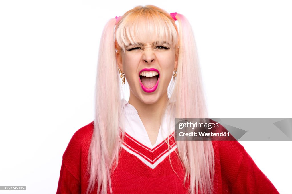 Beautiful young woman shouting with long pigtails against white background