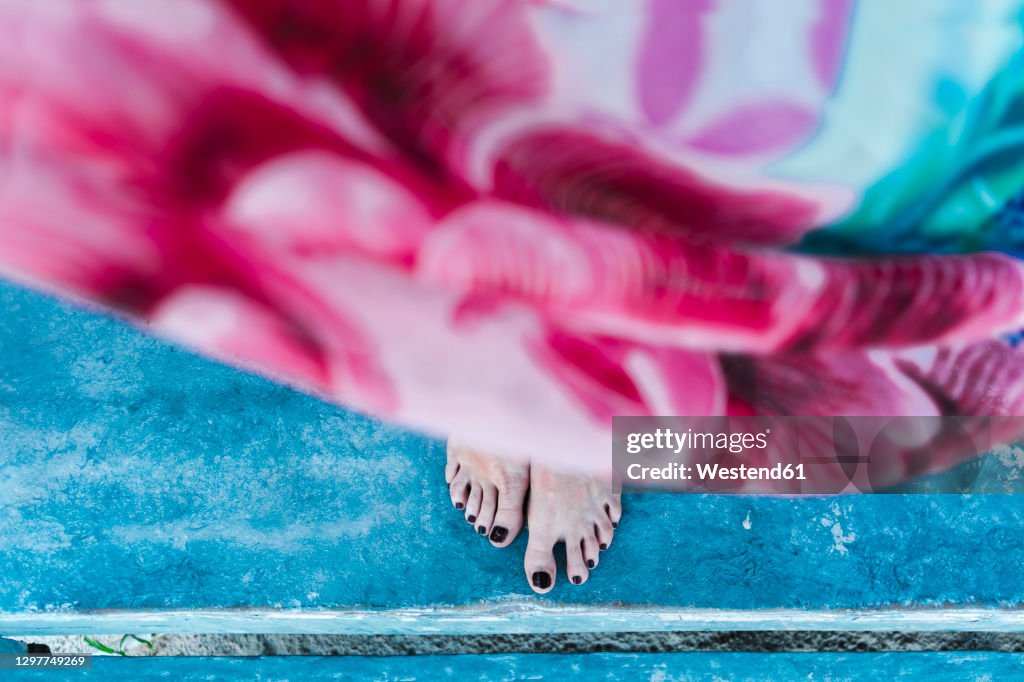 Woman's feet with black nail polish on shabby floor at cabin