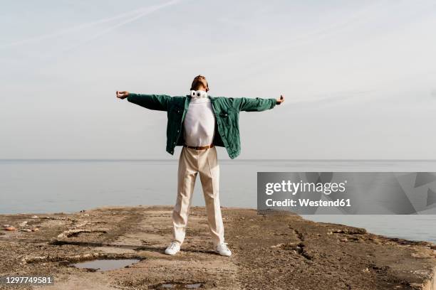 carefree man with arms outstretched against sea on pier - man outstretched arms stock-fotos und bilder