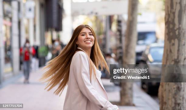 smiling woman spinning while standing on footpath in city - highlights hair stock pictures, royalty-free photos & images