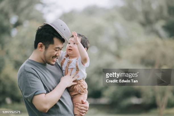 asiatiska kinesiska far bär sin son på allmän park under helgen bindning leker med hatt - baby carrier outside bildbanksfoton och bilder