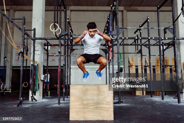 young athlete exercising box jumps at gym - entrenamiento combinado fotografías e imágenes de stock