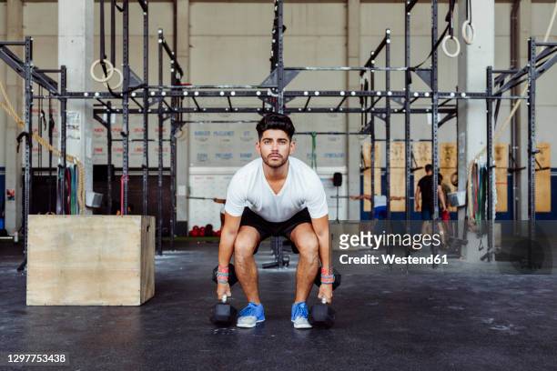 sportsman exercising weight lifting with dumbbells at gym - hombre agachado fotografías e imágenes de stock