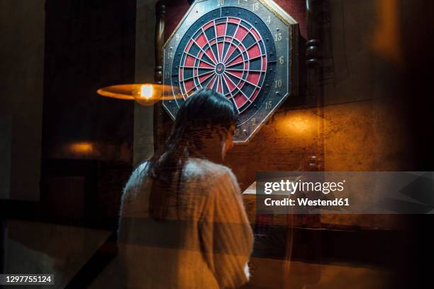 young woman playing darts in bar - cible de jeu de fléchettes photos et images de collection