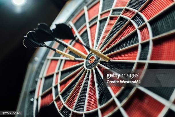 red and black dartboard with darts - freccette foto e immagini stock