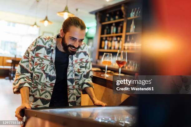 bearded man playing pinball in bar - pinball stock pictures, royalty-free photos & images