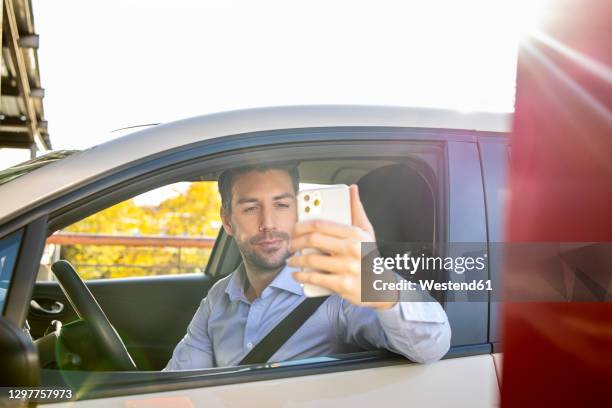 businessman paying through smart phone by meter at parking lot - parking meter fotografías e imágenes de stock