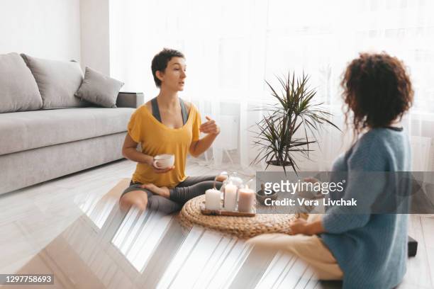 two woman sitting and drinking coffee after workout session at home. - life coach stock pictures, royalty-free photos & images