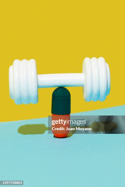 dumbbell on top of a pill - exercise pill stock-fotos und bilder
