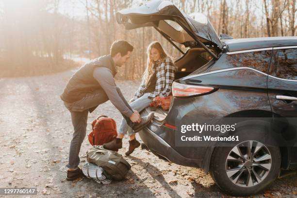 young couple leaving car before hiking in autumn forest - autumn car stock pictures, royalty-free photos & images