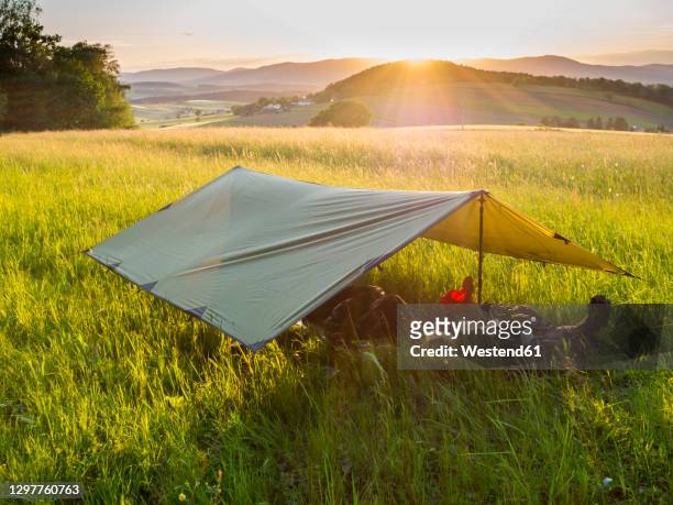 tarpaulin set in alpine meadow at sunset - plane stock-fotos und bilder