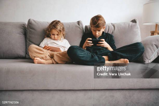 beautiful little girl and teenager boy with smartphone. leisure, children, technology and people concept - child mobile phone stock-fotos und bilder
