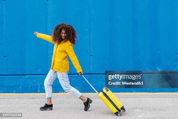 carefree woman running with luggage on footpath - mala de rodinhas - fotografias e filmes do acervo