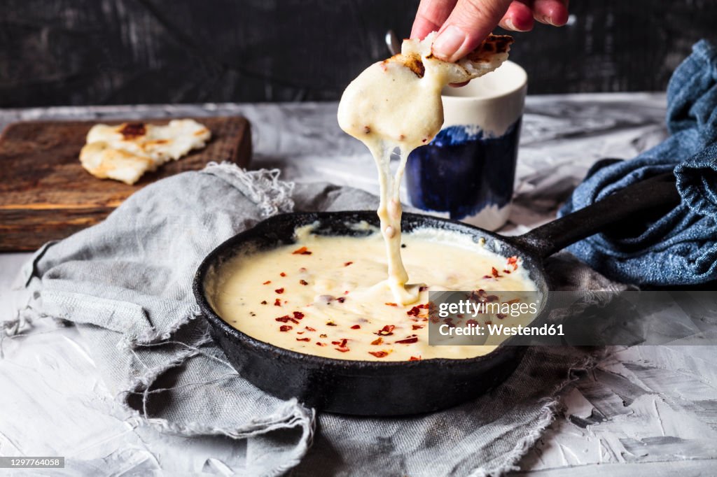 Woman picking Kuymak from cooking pan on table