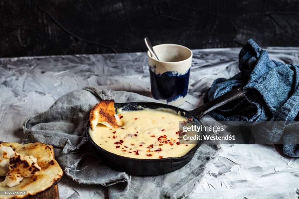 Kuymak in cooking pan by coffee cup on table