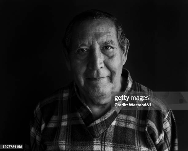 smiling senior man against black background - hispanic senior face stock-fotos und bilder