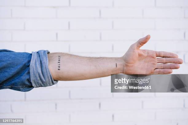 man's hand with tattoo against brick wall - tattoo fotografías e imágenes de stock