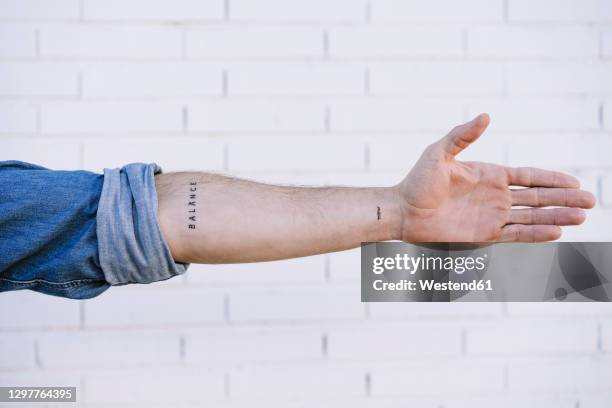 man's hand with tattoo against brick wall - mouw stockfoto's en -beelden