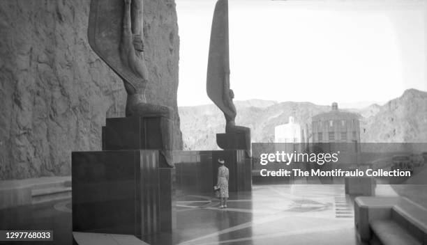 Woman beside the imposing Hoover Dam bronze Art Deco sculptures of Guardian Angels by sculptor Oskar Hansen a memorial to workers who lost their...