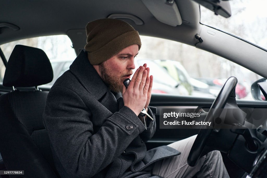 Fahrer heizt seine Hand in seinem Auto, so dass er sich ein wenig aufwärmen kann
