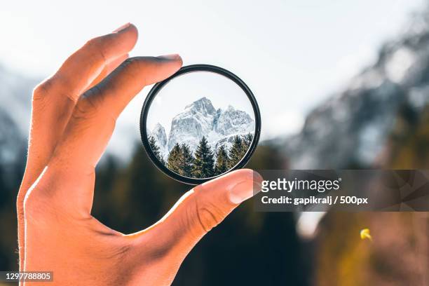 cropped hand holding a camera filter with view of mountain - enfoque fotografías e imágenes de stock
