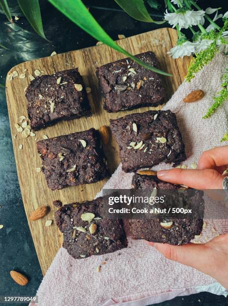 cropped hand of woman holding salted caramel chocolate brownies - salted brownie stock pictures, royalty-free photos & images