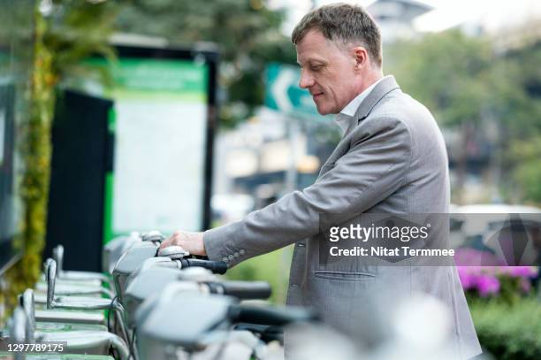 a businessman choosing bicycle in a public bicycle service area. bicycle-sharing system concepts. - government employee stock pictures, royalty-free photos & images
