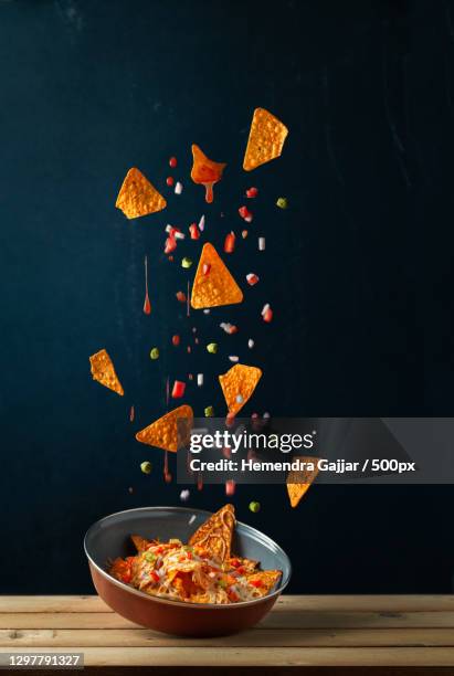 nachos levitating against black background,vadodara,gujarat,india - nachos fotografías e imágenes de stock