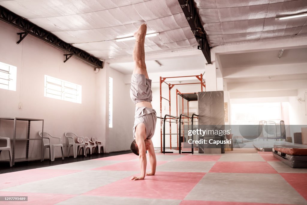 Male gymnast doing handstand on floor