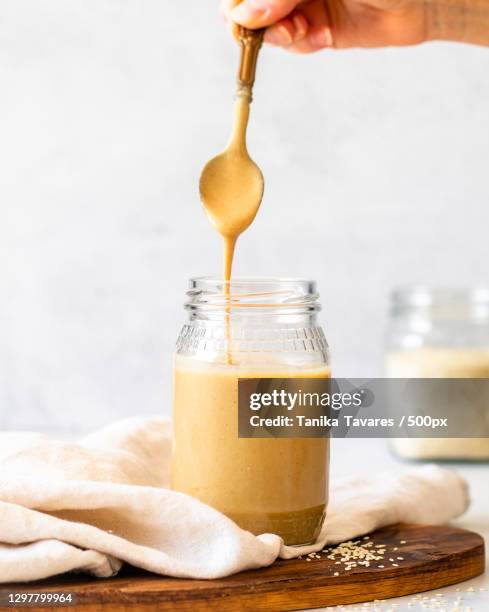 cropped hand of woman lifting spoon of tahini out of jar,south africa - tahini imagens e fotografias de stock