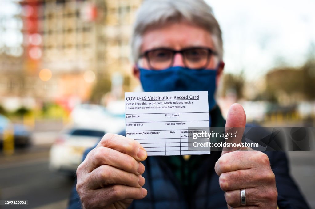 Senior man holding covid-19 vaccination record card