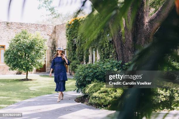 woman in an elegant blue evening dress walking through a garden - formal garden - fotografias e filmes do acervo