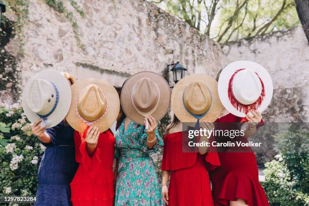 five women in colourful dresses holding a sombrero in front of their faces - party of five bildbanksfoton och bilder