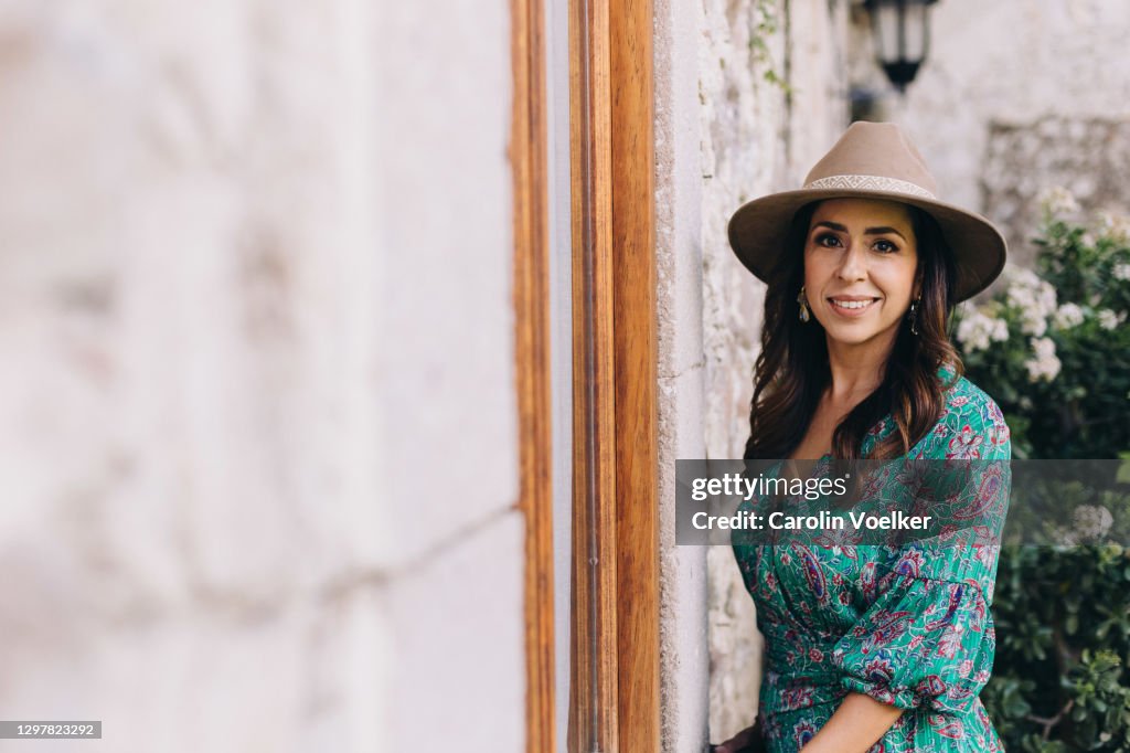 Latina woman with long hair and a colourful dress smiling at camera