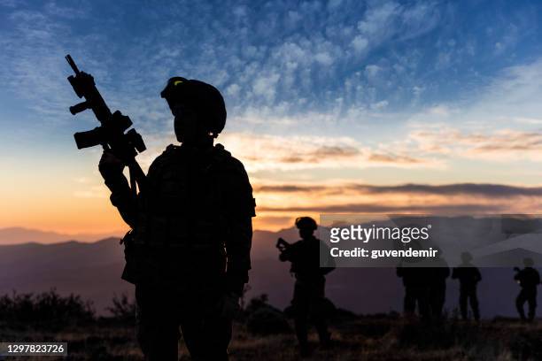 female soldier standing at sunset during a military mission - terrorism stock pictures, royalty-free photos & images