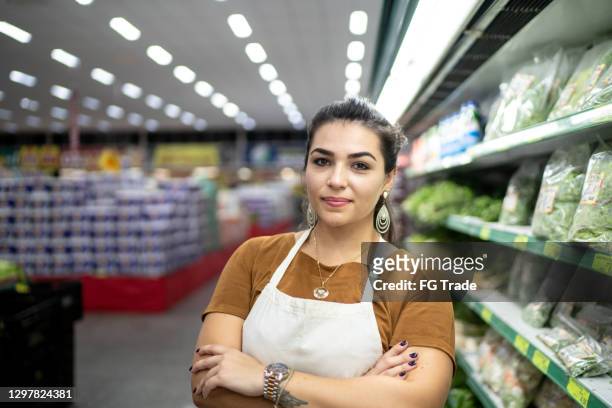portret van een jonge vrouw die in een supermarkt werkt - bio supermarkt stockfoto's en -beelden