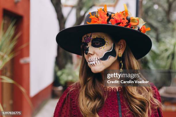 portrait of a woman with catrina face paint and a sombrero for day of the dead in mexico - day of the dead stock-fotos und bilder