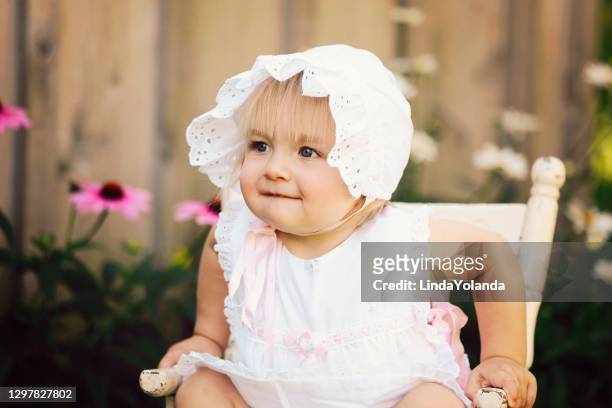 baby girl sitting in old wooden chair wearing vintage dress - hood clothing stock pictures, royalty-free photos & images