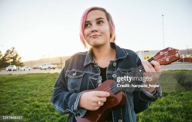 teenage girl holding a ukulele. - smirking stock pictures, royalty-free photos & images