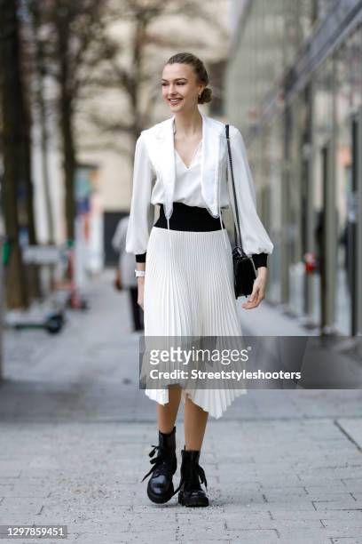 Actress Lilly Krug wearing black boots by Kennel & Schmenger, a black bag with silver studs by Yves Saint Laurent and a midi length black and cream...