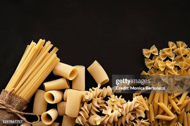 different types of dry pasta on dark background - dry pasta stock pictures, royalty-free photos & images