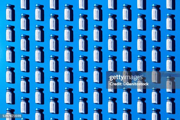 covid-19 vaccine vial pattern on blue background - phiole stock-fotos und bilder