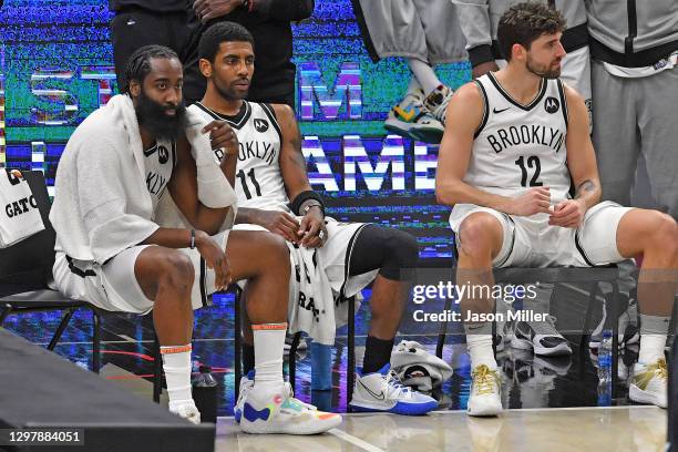 James Harden, Kyrie Irving and Joe Harris of the Brooklyn Nets sit on the bench during a timeout in the fourth quarter against the Cleveland...