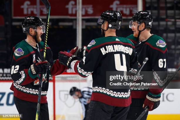 Jordan Oesterle of the Arizona Coyotes celebrates an empty-net goal with Niklas Hjalmarsson and Lawson Crouse during the third period of the NHL game...